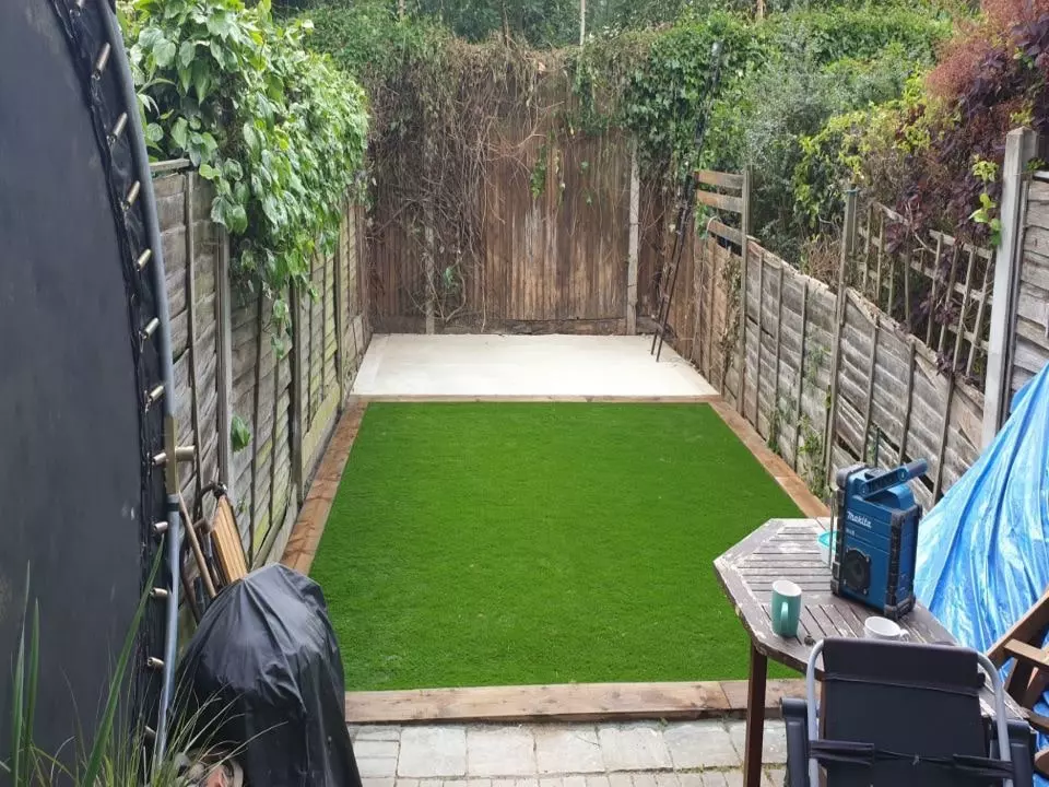 view of a garden from house with patio new artificial lawn and shed base installed