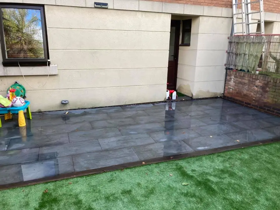 a newly installed porcelin slapped patio area that leads to artificial grass.